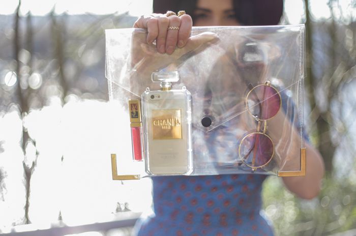 close up at bag clear plastic clutch bag, perfume iPhone case, chanel, ysl lipgloss